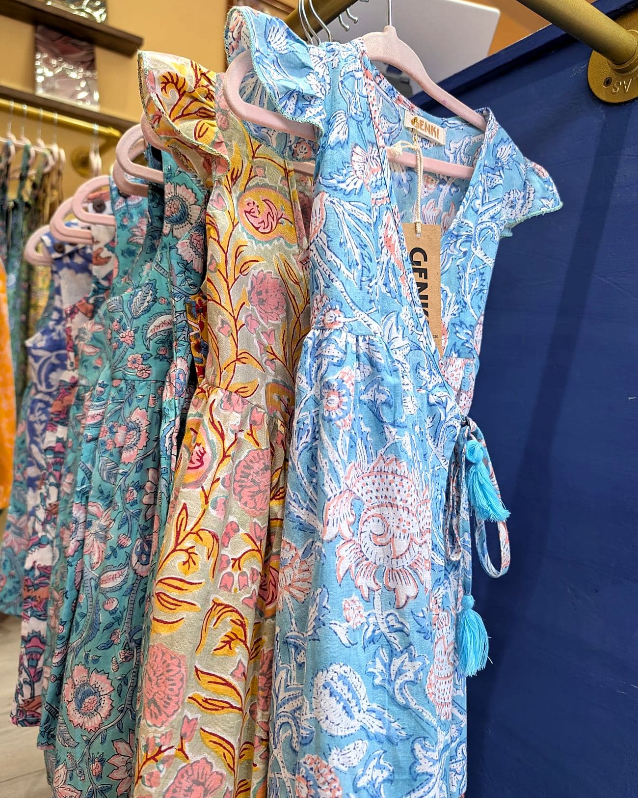 A rail of Genki Kids blockprinted dresses in blue, teal and yellow florals