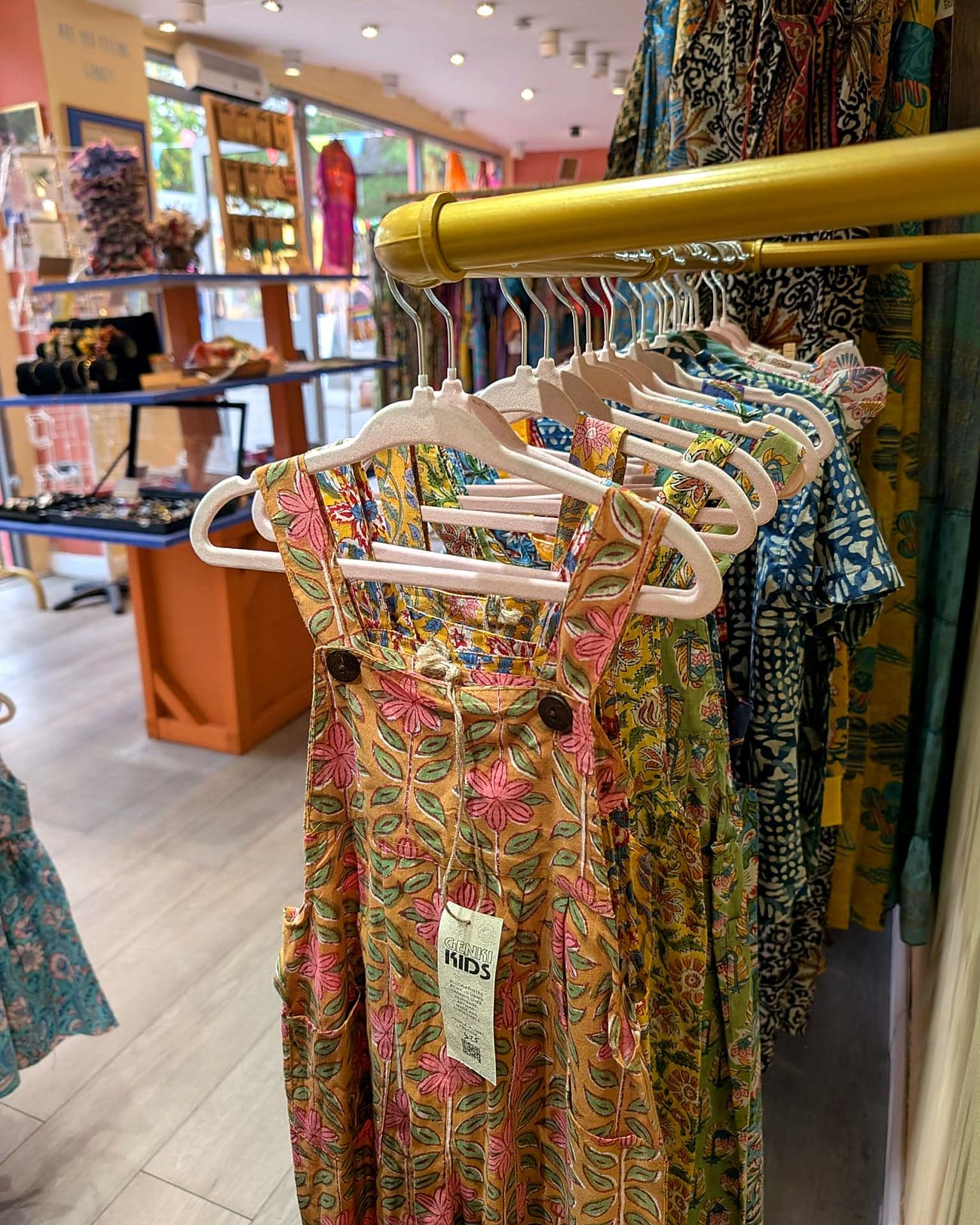 Genki Kids dungarees on a rail in the Southbank shop, with a swing tag showing