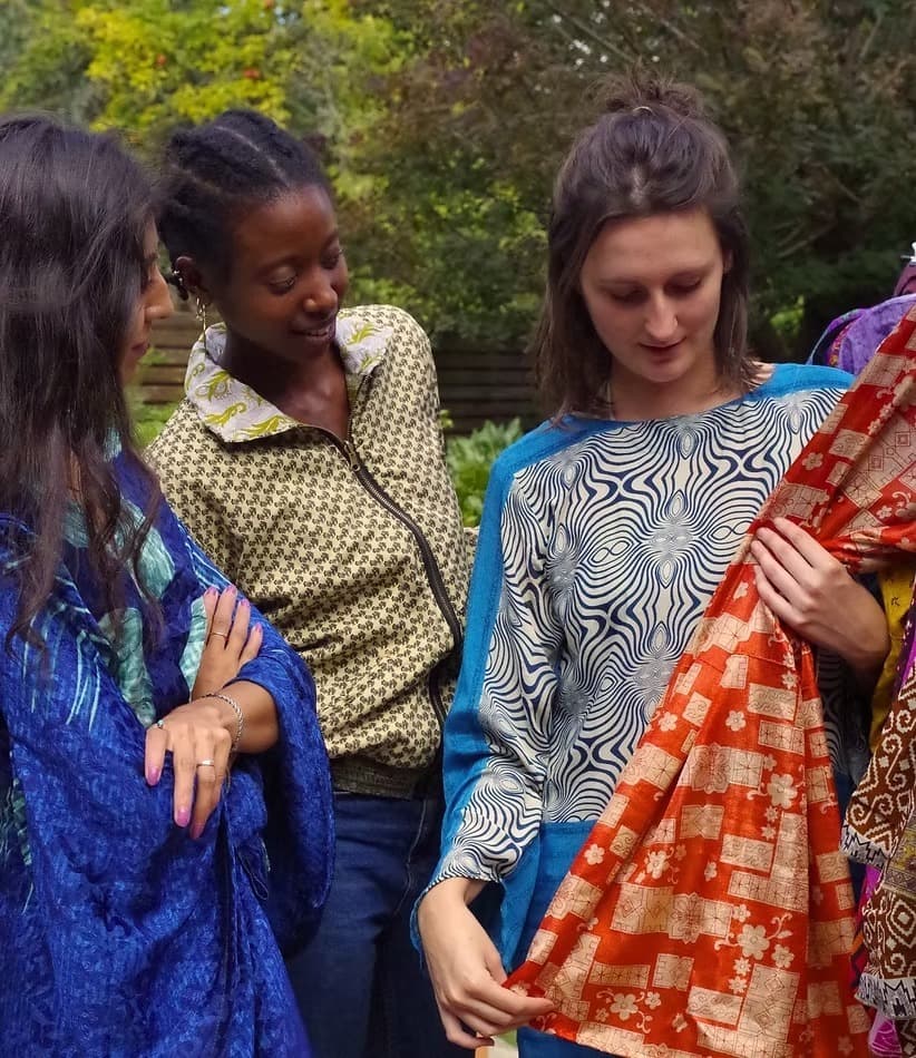 Three people looking through brightly printed fabrics together